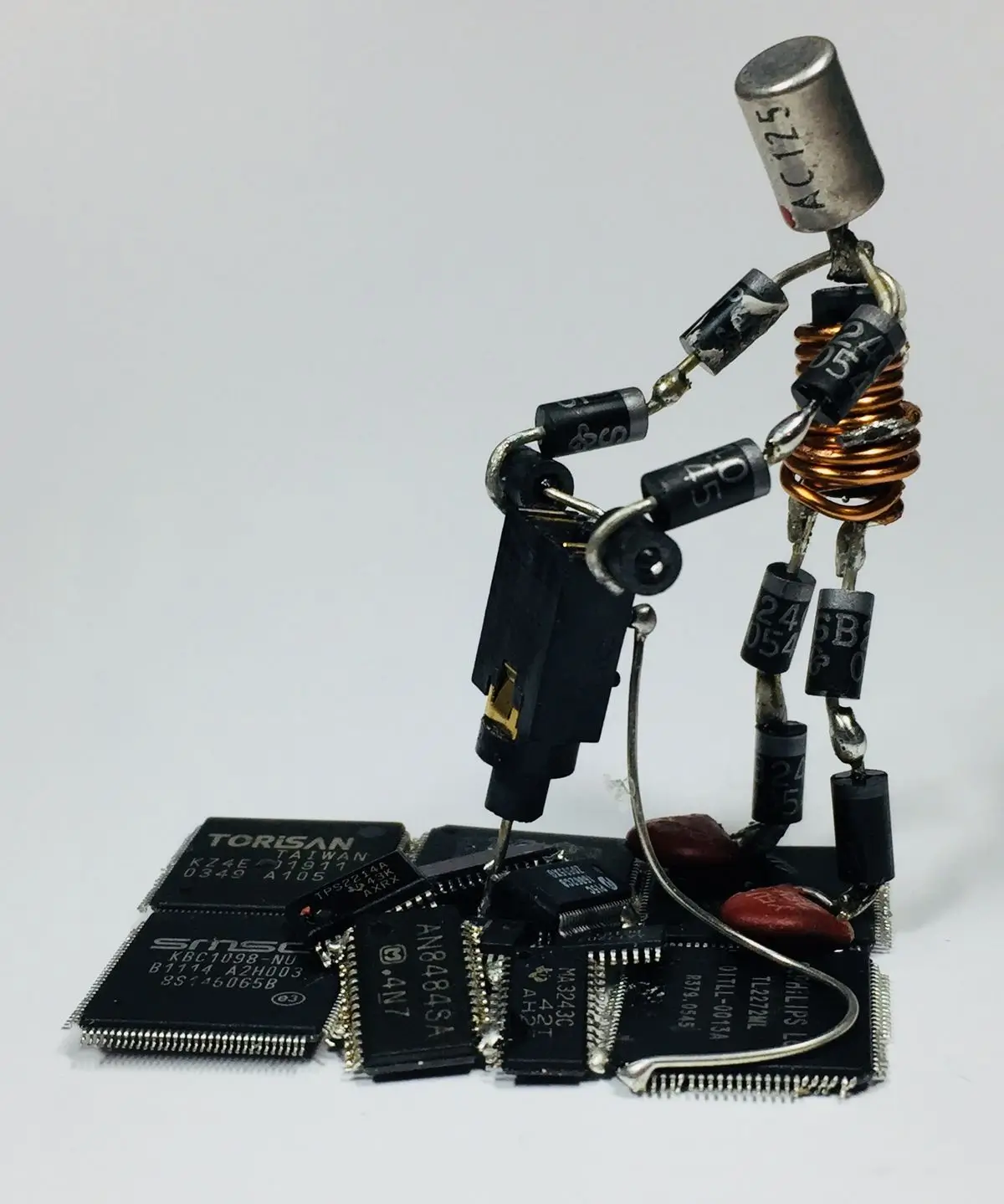 Boneco feito de componentes discretos soldados em posição de operação de uma betoneira em um chão de chips pretos