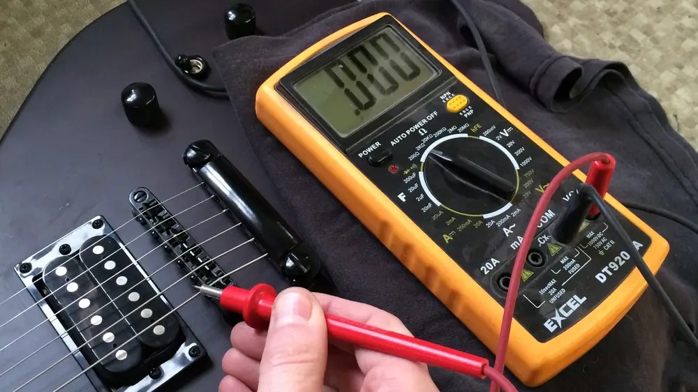 Guitarra eletrica preta com multimetro amarelo medindo continuidade