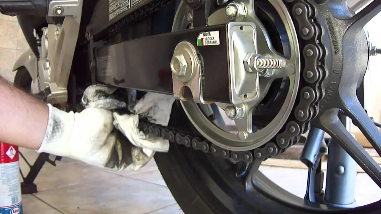 lubrificando a corrente da moto com as maos